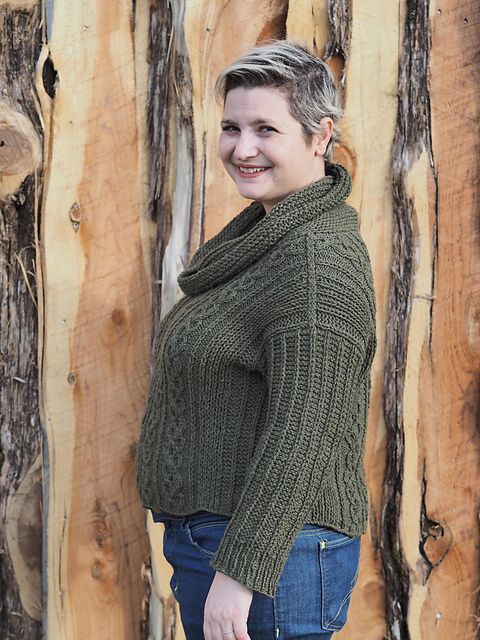 Beautiful Christina in a green cabled sweater, against a rustic wooden backdrop.