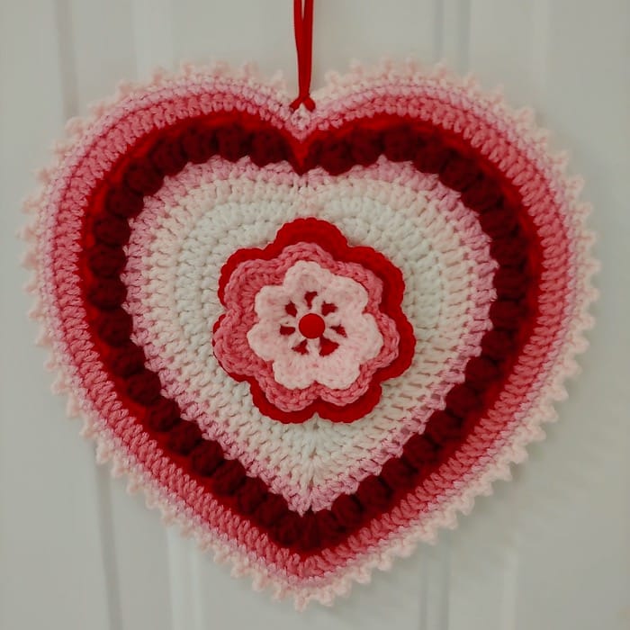 decorative hanging crocheted heart in white, pink, and red, with floral center