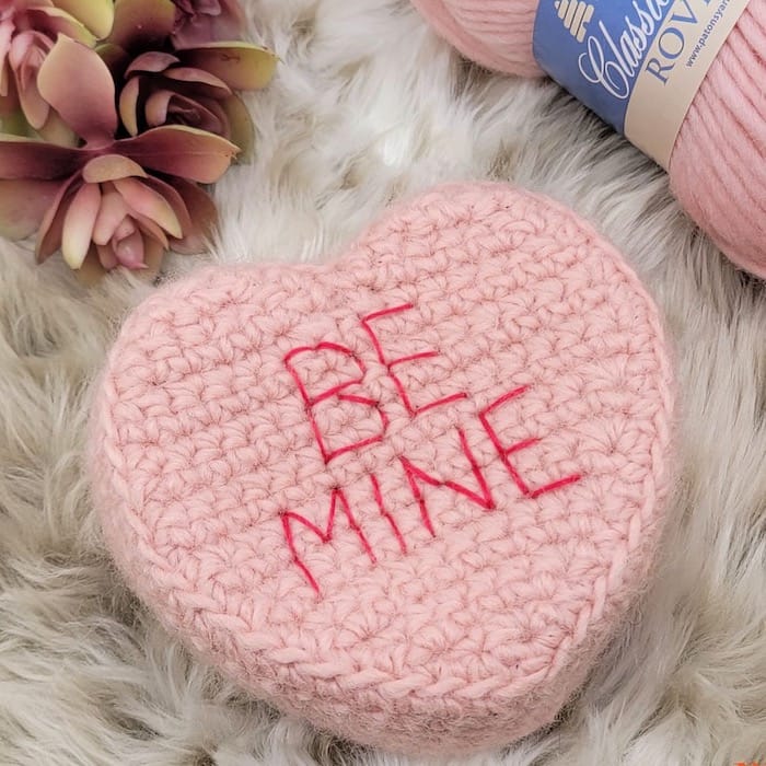 pink crocheted box resembling a conversation heart candy with the words "be mine" 