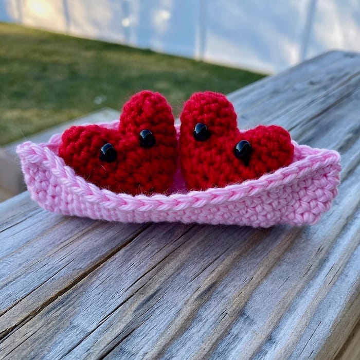 pink and red amigurumi project of a "pea" pod with heart-shaped peas