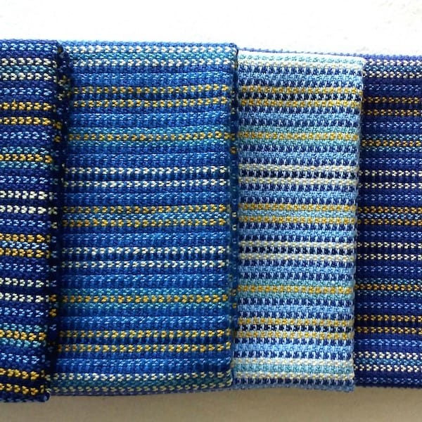 four hanging woven towels, mostly in rich blue with cream and yellow accent stripes