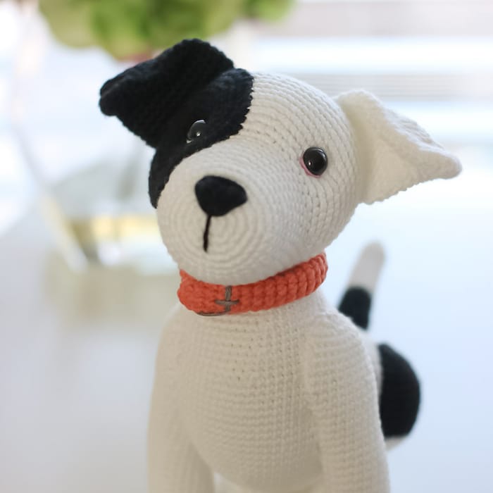 a cute little crocheted black and white staffy puppy with a bright orange collar